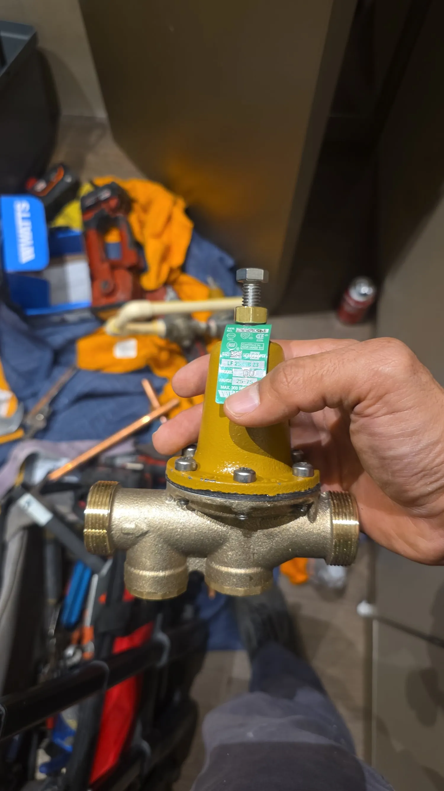 Plumber holding a new pressure reducing valve before installation