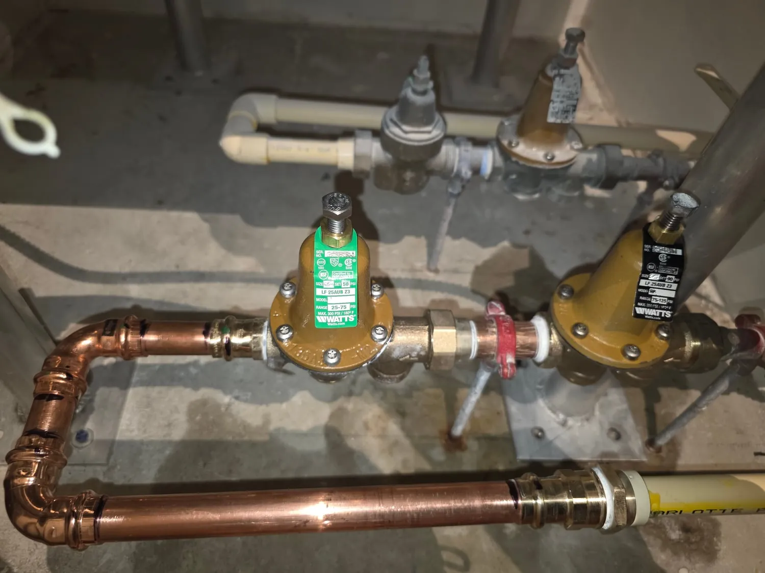 Two new pressure reducing valves on copper piping in a building mechanical room