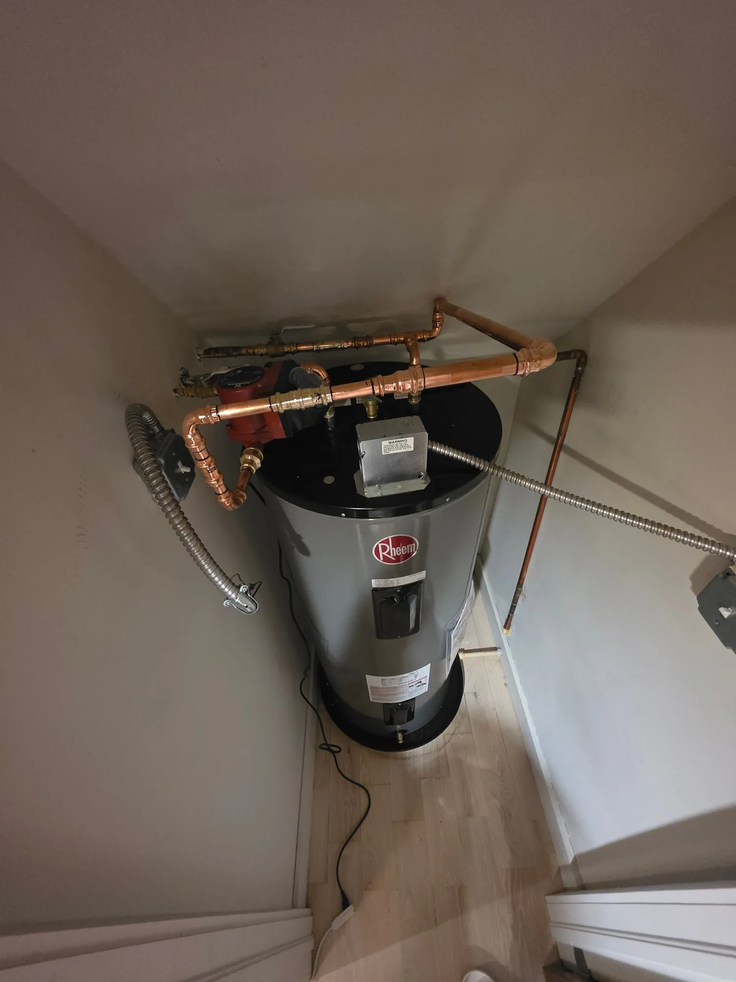 Rheem electric water heater with copper piping looping over to a recirculation pump
