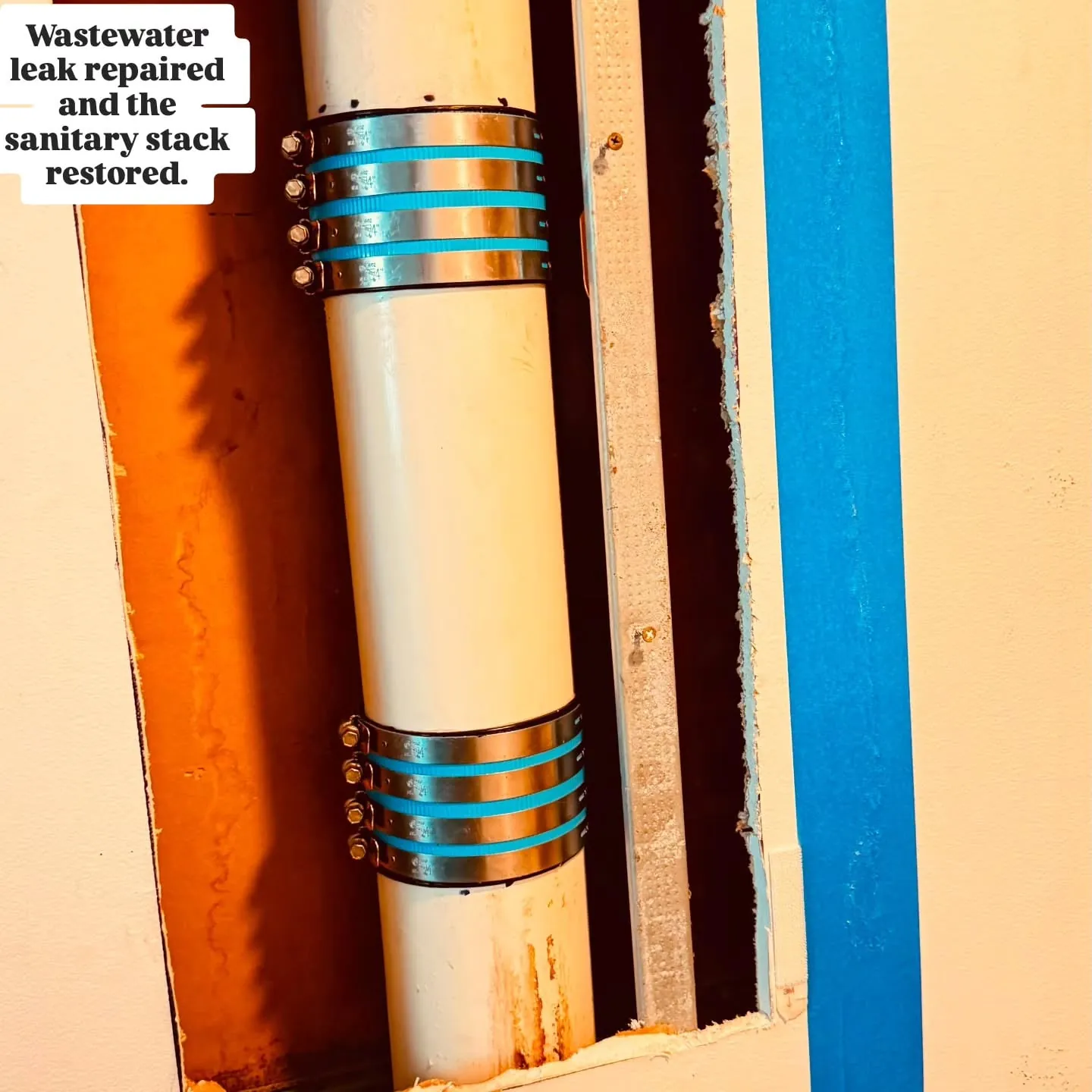 Repaired PVC stack with two shielded couplings visible in the open wall